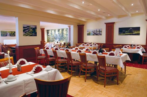 a dining room with white tables and chairs at AVALON Hotelpark Königshof in Königslutter am Elm
