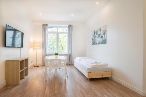 a white room with a bed and a table at RAJ Living - 1 or 3 Room Apartments - 20 Min Messe DUS and Old Town DUS in Düsseldorf