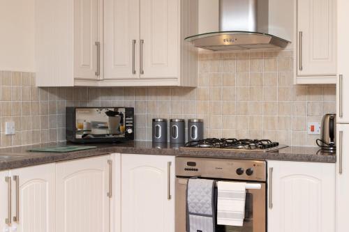 a white kitchen with a stove and a microwave at 1 Eureka Mews in Chester-le-Street