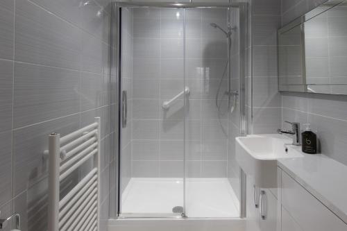 a white bathroom with a shower and a sink at 1 Eureka Mews in Chester-le-Street