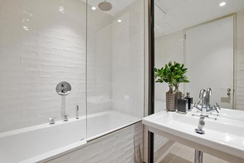 ein weißes Badezimmer mit Badewanne und Waschbecken in der Unterkunft Whitfield Street Residences by Aeria Apartments in London