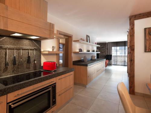 una cocina con armarios de madera y un aparato rojo en Apartment Mountain Resort C15 by Interhome, en Kaprun