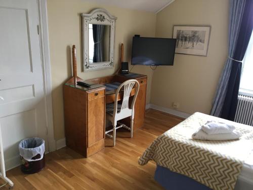a bedroom with a desk with a mirror and a bed at Kolbäcks Gästgivaregård in Kolbäck