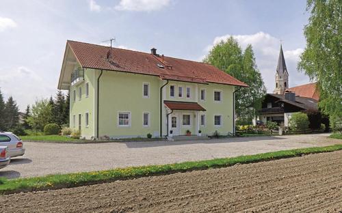 une maison jaune dans une rue avec une église dans l'établissement Haus Birgit, à Bad Füssing