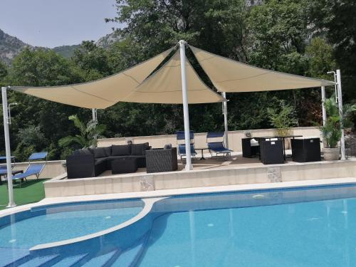 un dosel de bronceado sobre una piscina con sillas y un sofá en Apartments Villa Eden, en Kotor