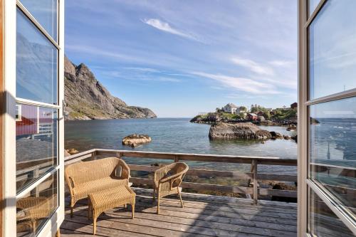 a balcony with two chairs and a view of the ocean at Lofoten Cottages in Nusfjord