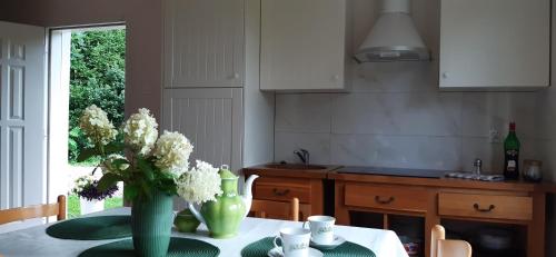 eine Küche mit einem Tisch und einer Blumenvase darauf in der Unterkunft Domek - Apartament in Łapalice