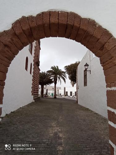 an archway in a building with palm trees in the background at Precioso apartamento con terraza en Teguise in Teguise