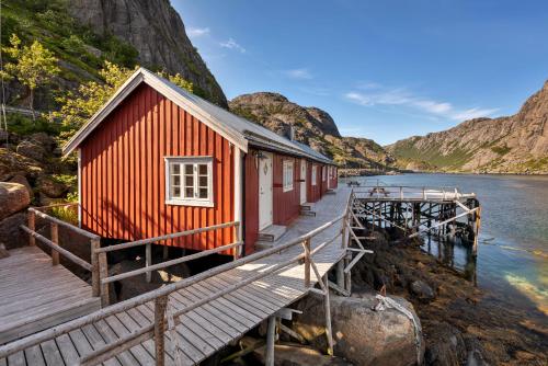 a red building on a dock next to a body of water at Lofoten Cottages by Nusfjord in Nussfjord