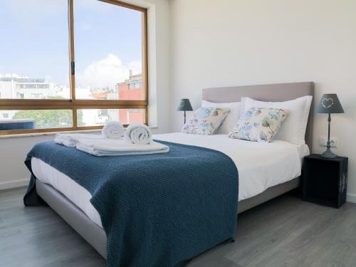 1 dormitorio con 1 cama con manta azul y ventana en CM VINTAGE Apartments - Breiner, en Oporto