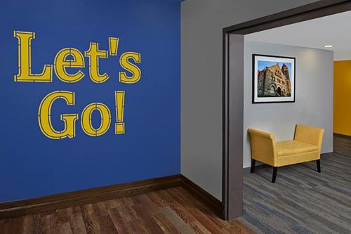 a waiting room with a yellow chair and a blue wall at Scholar Morgantown, Tapestry Collection by Hilton in Morgantown
