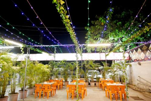 a patio with orange tables and chairs and lights at Hotel Sagar in Kalyan