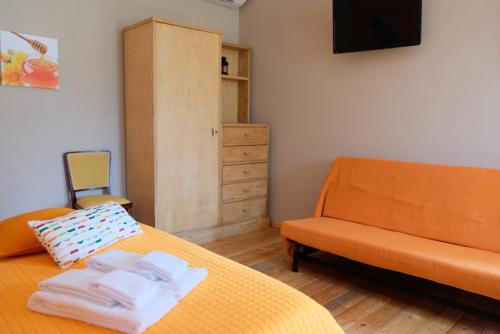 a bedroom with an orange bed and a couch at Agriturismo Quartuccio in Oricola