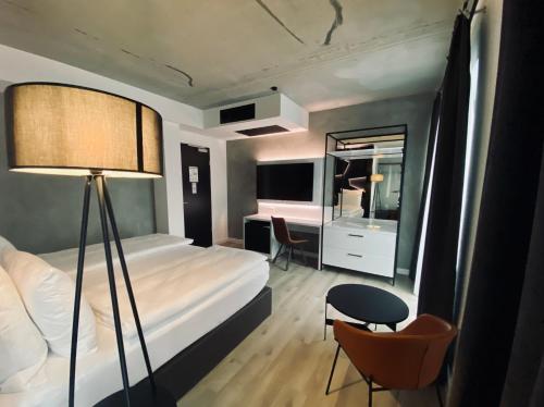 - une chambre avec un lit, un bureau et une chaise dans l'établissement DORMERO Hotel Aschaffenburg, à Aschaffenbourg