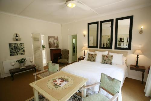 ein Schlafzimmer mit einem weißen Bett sowie einem Tisch und Stühlen in der Unterkunft Bordeaux Haven Guest House in Vereeniging