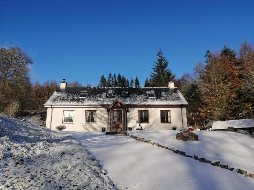 a small white house in the snow with trees at Corrie View in Invergarry