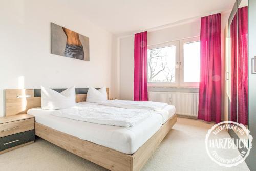 ブラウンラーゲにあるBlockhäuser Fewo2 Harzblickのベッドルーム1室(赤いカーテン付きの大型ベッド1台付)