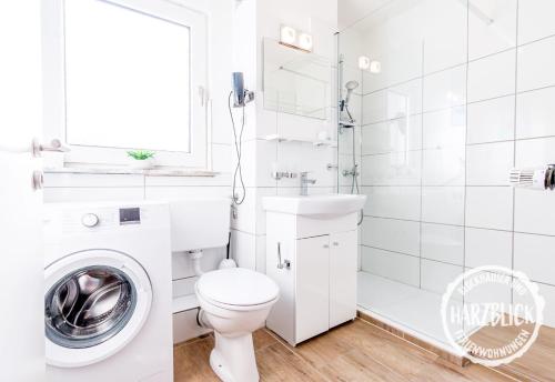 a white bathroom with a toilet and a washing machine at Blockhäuser Fewo2 Harzblick in Braunlage