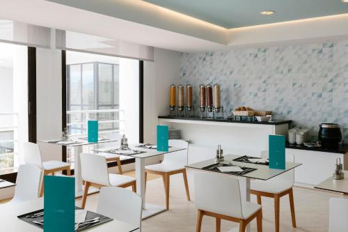 Un comedor con mesas blancas y sillas blancas. en Bordoy Alcudia Bay - Adults Only, en Puerto de Alcudia