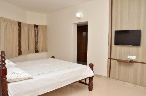 a bedroom with a bed with a tv on the wall at Serenity Manor in Coonoor