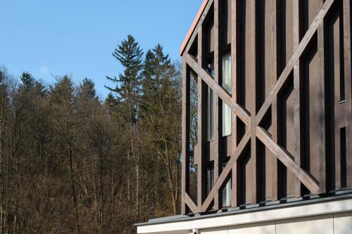 a building with a wooden facade with trees in the background at Hotel Čad in Ljubljana