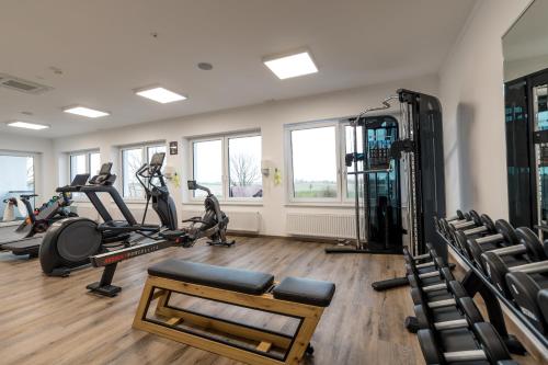 a gym with treadmills and ellipticals in a room at Waldhotel zum Bergsee Damme in Damme