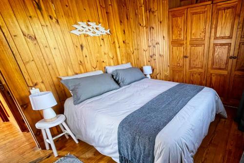 1 dormitorio con 1 cama y pared de madera en 16 Dune Park en Keurboomstrand