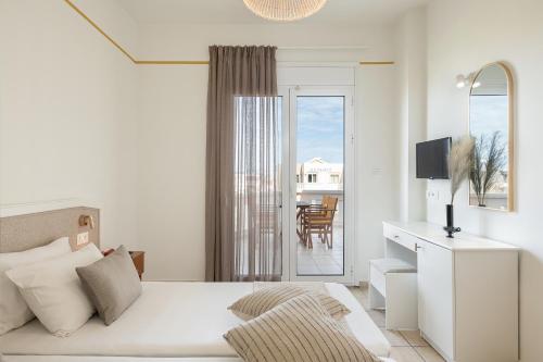 a white bedroom with a bed and a balcony at Artemis Apartments in Stalos