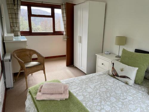 um quarto com uma cama, uma cadeira e uma janela em Ardgarry Farm em Invergarry