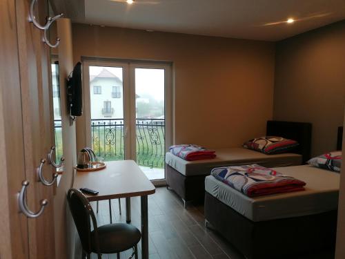 Zimmer mit 2 Betten, einem Tisch und einem Fenster in der Unterkunft POKOJE GOŚCINNE AZALIOWA 34 Mielno in Mielno