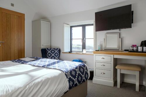 a bedroom with a bed and a desk with a television at Victoria Inn Brewhouse B&B in Roch