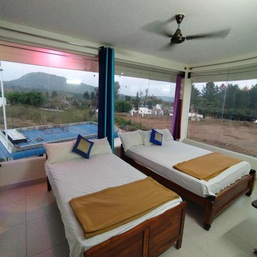 two beds in a room with a large window at Green Apple Resorts in Yelagiri
