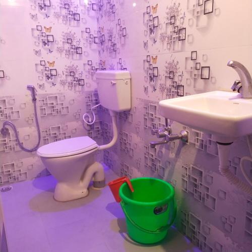 a bathroom with a toilet and a sink and a bucket at Green Apple Resorts in Yelagiri