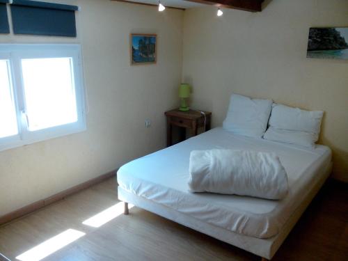 - une chambre avec un lit doté de draps blancs et une fenêtre dans l'établissement Cabanon du Pêcheur, Parc National des Calanques, à Marseille