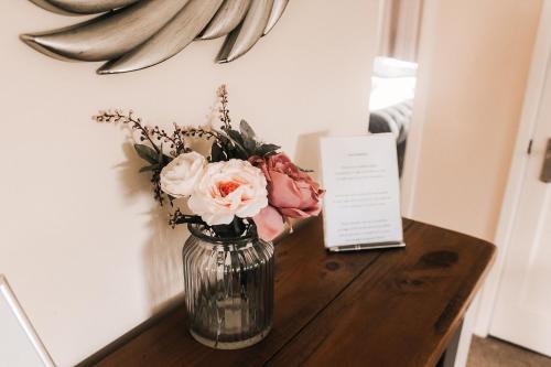 a vase with flowers sitting on a wooden table at Keer Side Lodge, Luxury lodge with private hot tub at Pine Lake Resort in Carnforth