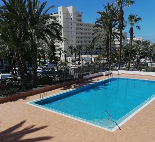 una grande piscina con palme e un edificio di KC home abroad a Playa de las Americas