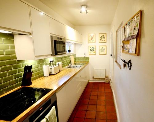 鐵橋的住宿－Victoria Cottage, Ironbridge，厨房配有白色橱柜和台面