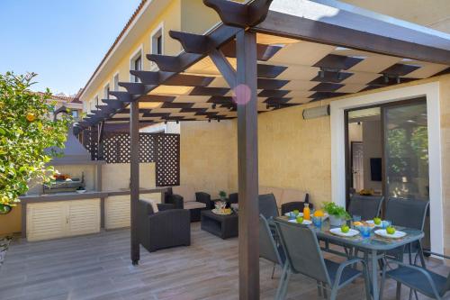 a patio with a table and chairs under a pergola at Protaras Villa Angela Nefeli in Paralimni