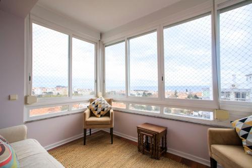 a living room with large windows and a chair at VistaoMar in São João do Estoril