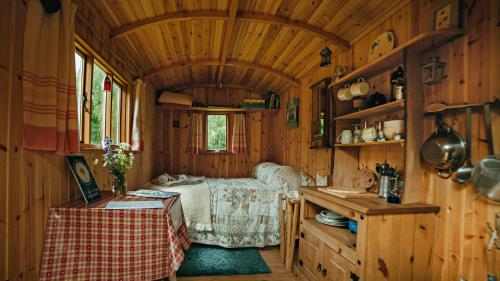 een slaapkamer met een bed in een houten kamer bij Cosy woodland off Grid Shepherds Hut - Rowan in Castle Douglas