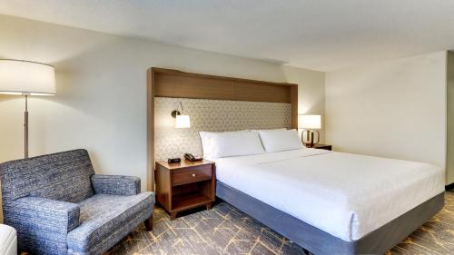 a hotel room with a bed and a chair at Holiday Inn Staunton Conference Center by IHG in Staunton