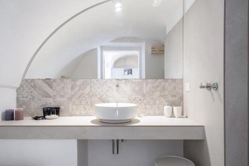 a white bathroom with a sink and a mirror at Palazzo Rapanà - Luxury Apt with hydromassage pool in Ostuni