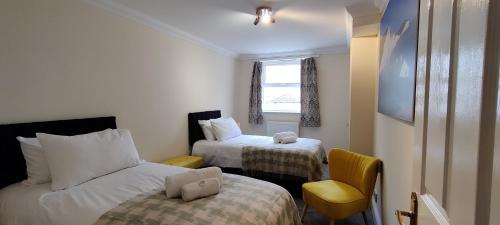 a small room with two beds and a chair at 6 Queens Gardens in Eastbourne