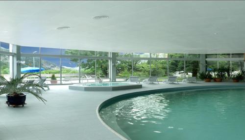 a large swimming pool in a building with chairs at Thermalhotel Regina Terme in Leukerbad