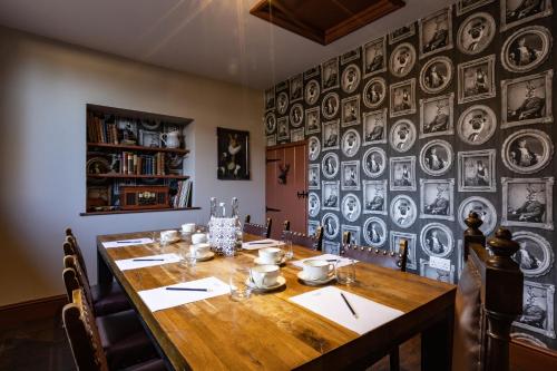 a dining room with a wooden table and a wall of plates at The Bull And Swan in Stamford