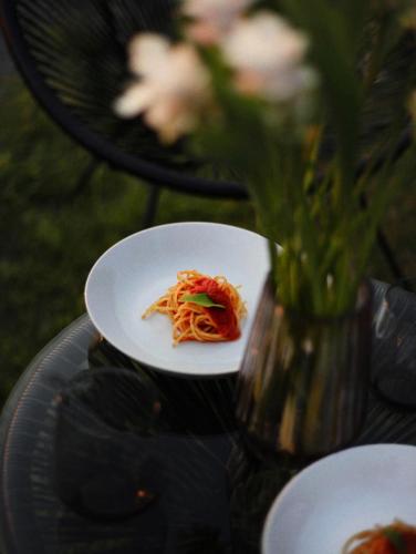 a plate of pasta and a vase of flowers on a table at Secret Garden Resort & Spa in Palma Campania