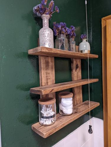 a wooden shelf with jars and flowers on a green wall at Cosy 2-Bed Property in Ashburton Dartmoor in Newton Abbot