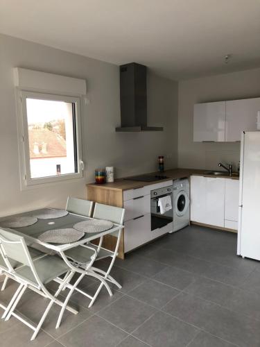 une cuisine avec une table et des chaises et un micro-ondes dans l'établissement Résidence Neuve entre montagne et lac, à Aix-les-Bains