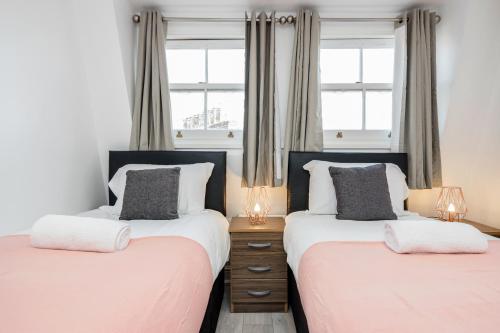 dwa łóżka w sypialni z dwoma oknami w obiekcie Cosy and Functional 1 bedroom flat in London w Londynie