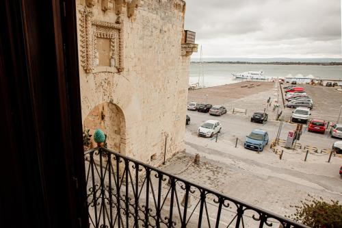 a person standing on a balcony looking at a parking lot at Palazzo Giunta - Porta Marina Ortigia in Siracusa